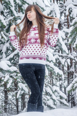 A girl in a sweater on the background of snow-covered trees . Girl winter on stroll. Winter fairy tale. Christmas trees in the snow