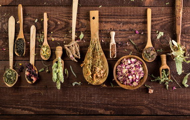 Assortment of dry tea in spoons on a wooden background. Top view.