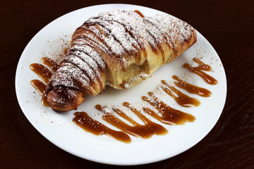 croissant on a plate with jam in icing sugar	
