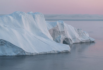 Iceberg at sunset. Nature and landscapes of Greenland. Disko bay. West Greenland. Summer Midnight Sun and icebergs. Big blue ice in icefjord. Affected by climate change and global warming.