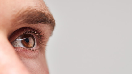 Extreme Close Up Of Eye Of Man Against White Studio Background