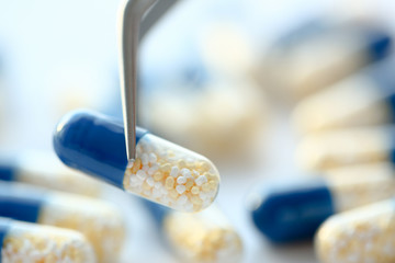 Arm lifting up pill with tweezers closeup