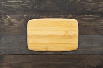 Cutting board on old dark wooden kitchen table. Top view, flat lay.