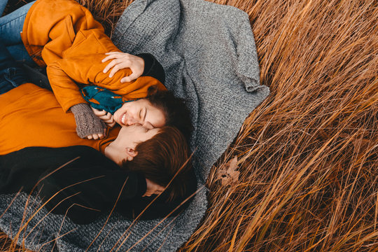 Young man and woman are lying and hugging in the autumn field.