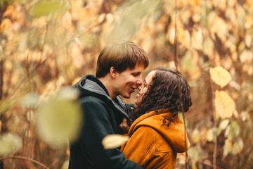 Young man and woman kiss in the autumn forest.