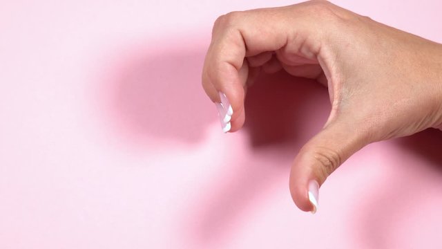 Woman making heart gesture with 2 hands isolated on pastel pink background. Real time full hd video footage.