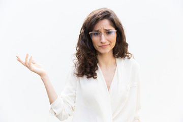 Careless woman in glasses pointing hand at empty copy space. Wavy haired young woman in casual...