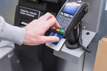 Man paying at the self-service counter entering credit card pin code for security password in credit card swipe machine. shopping time