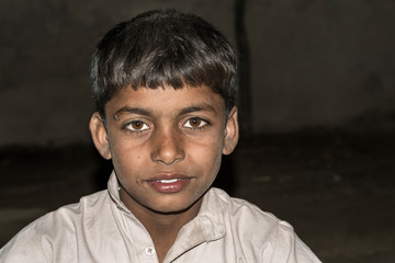 closeup of a poor staring hungry orphan boy in a refugee camp with sad expression on his face and...