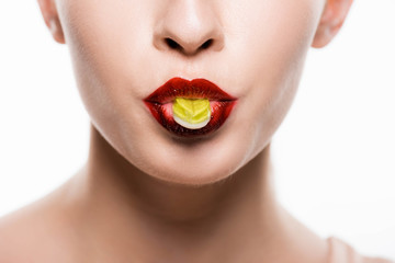 cropped view of woman with red lips holding candy in mouth isolated on white