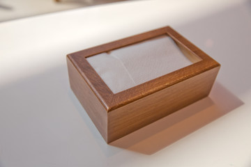 Wooden napkin holder with paper serviettes . Wooden brown empty napkin box . wooden stand with salt shaker, napkins on a wooden table in a cafe .