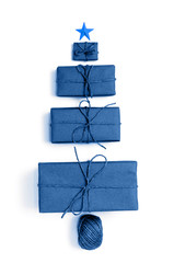 Christmas tree made of gift boxes wrapped with trendy classic blue paper. Color trend 2020. Christmas, winter, New Year holidays concept. Holiday shipping. Flat lay, top view
