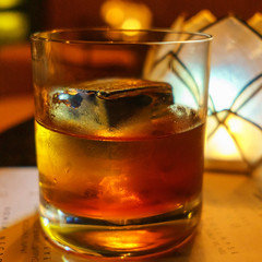 Glass of whiskey on a black wooden table in a bar