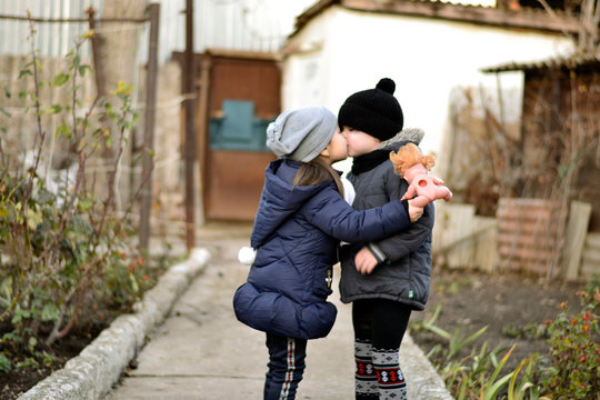 Funny little boy and girl in autumn clothes kissing 