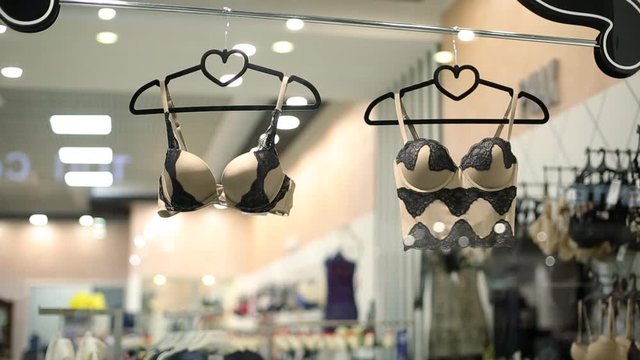 Female lingerie store showcase. Bras on hangers. High-quality women underwear boutique. Different styles and patterns of bras. Attractive romantic and home clothes shop.