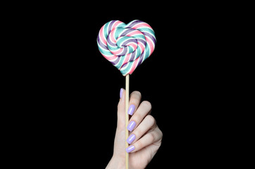 girl with beautiful manicure holding a big Lollipop in the shape of a heart