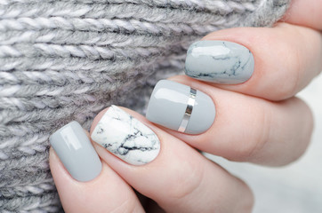 manucure en marbre gris blanc avec bande argentée sur fond gris