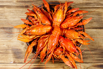 Boiled crayfish in plate on wooden table. Top view