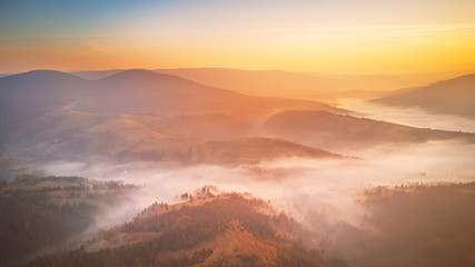 Sunrise over mountain foggy valley. Misty woodland in the morning