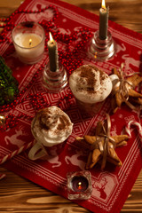 Top view of hot cinnamon creamy drinks in Christmas decoration and burning candles 