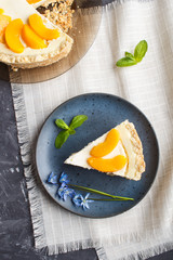 A piece of peach cheesecake on a blue ceramic plate with blue flowers on a black concrete background. top view, copy space.