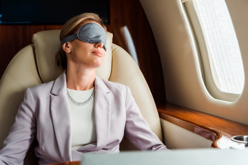 Businesswoman with sleeping mask sitting in private plane