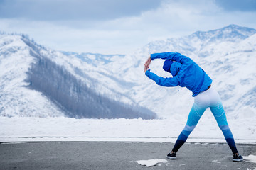 Athlete at the top of the mountain doing stretching.