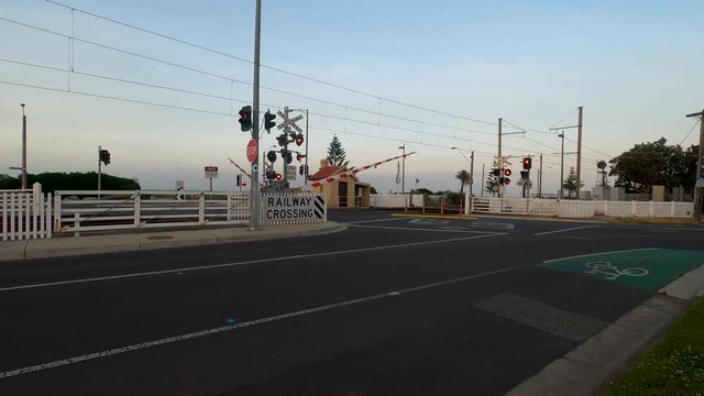 Railway level crossing boom gates and red lights flashing.
