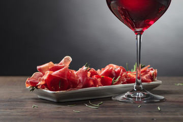 Prosciutto with  rosemary and glass of red wine .