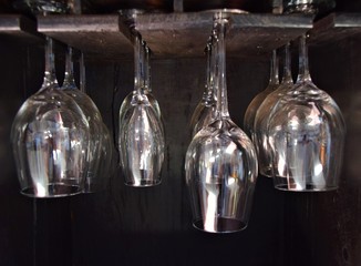 Various wine glasses hanging in bar with black background