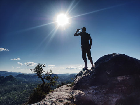 Traveler on rock drinking bottled water from plastic bottle