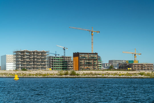 Residential construction on the Northern part of Amsterdam, the Netherlands. Modern waterfront apartment buildings, tower cranes, construction site, river IJ. New houses for sale.