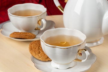 White porcelain cup of tea and oat cookies on a table