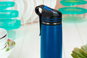Thermos bottle against tableware in a kitchen