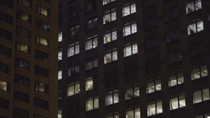 Generic night time establishing shot of typical apartment or office building in the dark. NX exterior of building with illuminated windows from inside