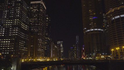 Night time exterior establishing shot of riverfront skyline in Chicago. Generic urban skyscraper apartment buildings illuminate dark sky
