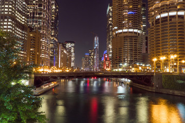 Night time exterior establishing shot overlooking Chicago river front area with skyline illuminated in dark sky reflecting off water in beautiful scene