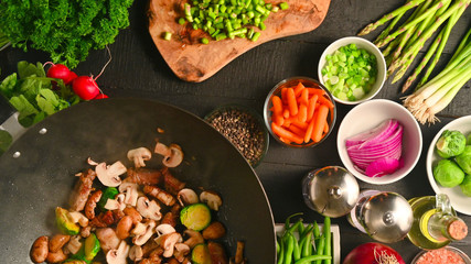 Cooking meat with vegetables, in a wok, on a background with vegetables