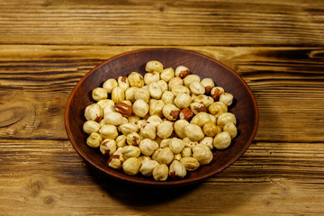 Peeled hazelnuts in ceramic plate on wooden table