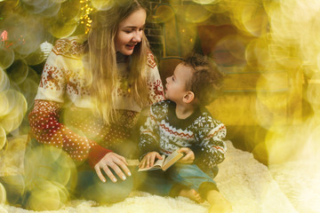 Happy smiling mother and son in christmas sweaters with golden bokeh. Christmas decoration.
