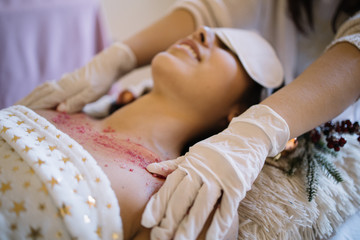 Obraz na płótnie Canvas SPA therapist's hands applying scrub on womans chest