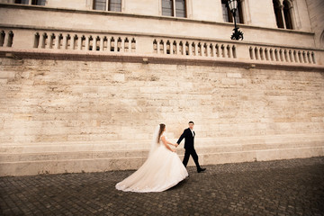 Bride and groom hugging in the old town street. Wedding couple walks in Budapest near Parliament...