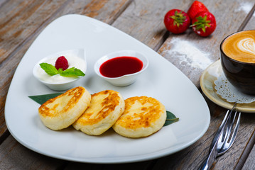 Traditional breakfast with coffee and cheesecakes, cottage cheese pancakes on a plate with syrup and jam.