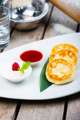 Traditional breakfast with coffee and cheesecakes, cottage cheese pancakes on a plate with syrup and jam.