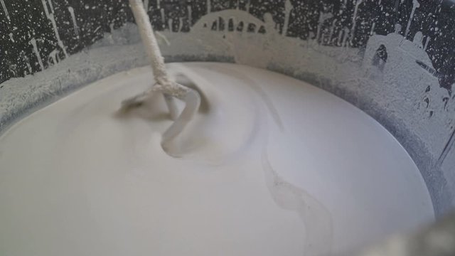 Workers knead a white solution in a bucket. The mixture for the bulk floor is stirred in a bucket. Plasterer knead the solution with a perforator