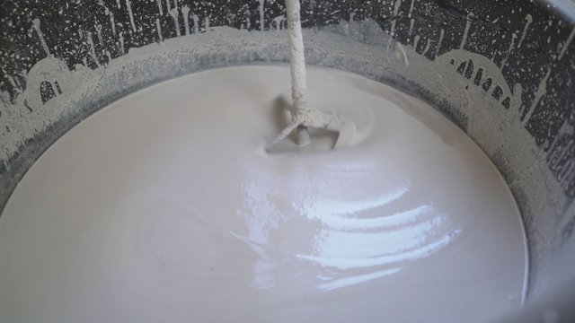 Plasterer knead the solution with a perforator. Workers knead a white solution in a bucket. The mixture for the bulk floor is stirred in a bucket.