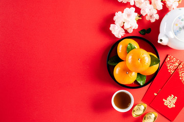 Chinese new year festival decorations pow or red packet, orange and gold ingots or golden lump on a red background. Chinese characters FU in the article refer to fortune good luck, wealth, money flow.