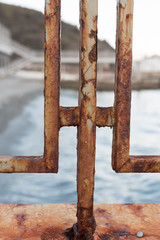 Oxidation of a rusty fence, a fragment on the embankment of the sea.