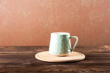 Clay cup on a wooden board on a dark background.