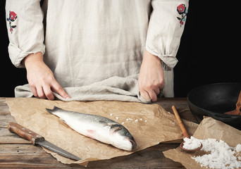 fresh whole sea bass fish lies on the table, cooking process